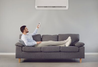 Homem ligando o ar-condicionado no sofá - Foto: Canva
