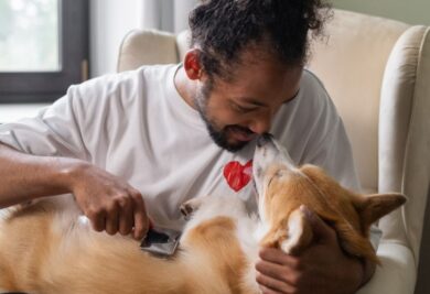 Homem interagindo com o seu cachorro enquanto escova os pelos do pet. Foto: Canva.
