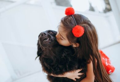 Menina dando um beijo no seu cachorrinho. Foto: Canva.